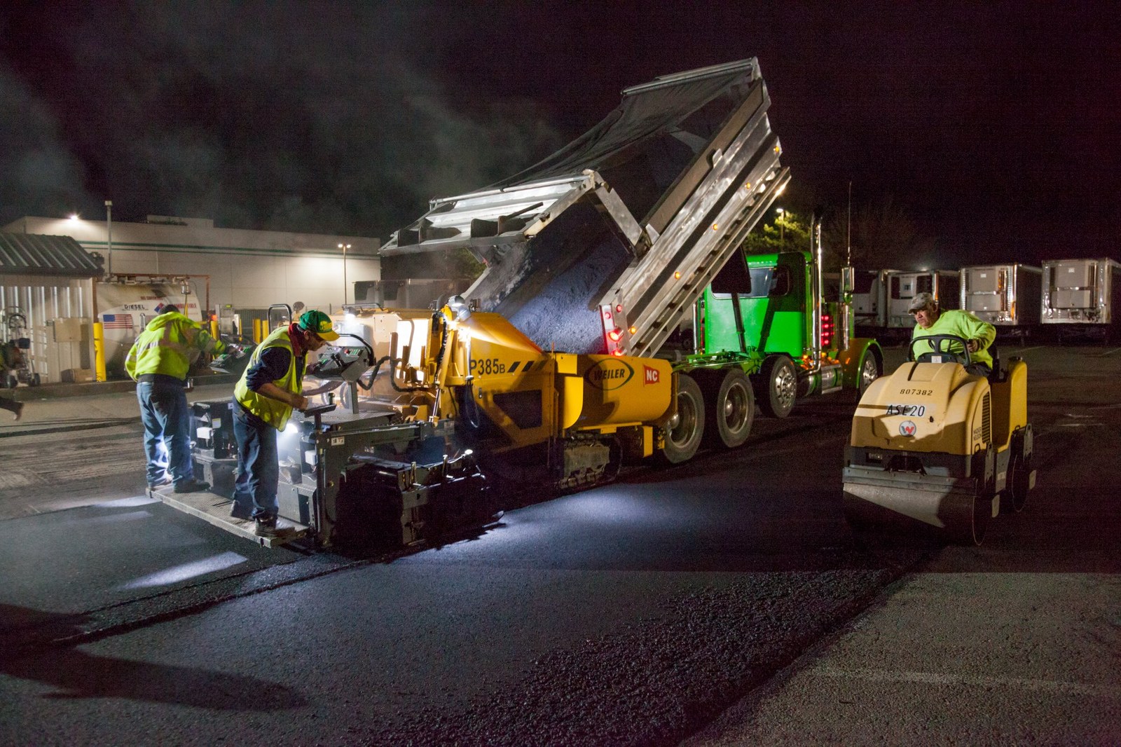 AC Moate Industries paving crew laying hot-mix asphalt at night, commercial parking lot