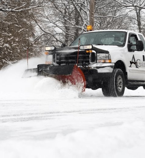 AC Moate Industries snow plow truck clearing commercial parking lot in winter